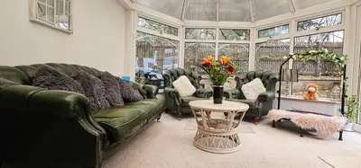 a living room with a green couch and a table with flowers at Boghead Cottage The West Wing in Bathgate