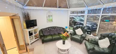 a living room with couches and a table with flowers at Boghead Cottage The West Wing in Bathgate