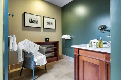 a bathroom with a sink and a vanity with a chair at Ugadale Cottages in Machrihanish