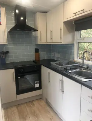 a kitchen with white cabinets and a sink and a stove at The Art Studio Arran in Isle of Arran