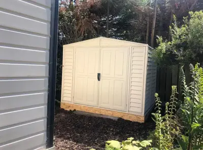 a white shed sitting next to a garden at The Art Studio Arran in Isle of Arran