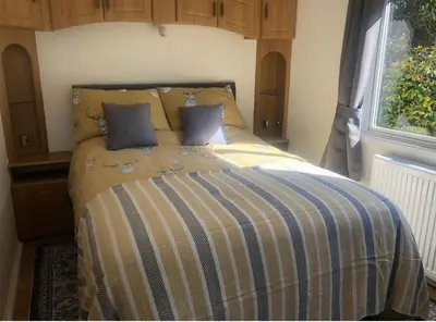 a bedroom with a bed with a striped comforter and a window at The Art Studio Arran in Isle of Arran
