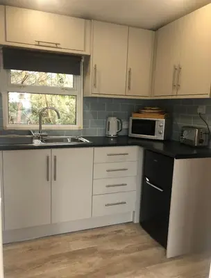 a kitchen with white cabinets and a sink and a microwave at The Art Studio Arran in Isle of Arran