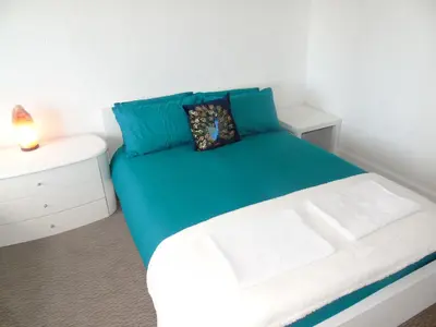 a bedroom with a green bed with a night stand at Snug - Grian-aig Apartment in Greenock
