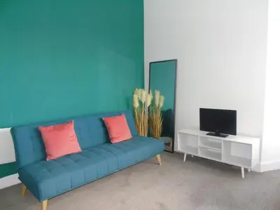 a living room with a blue couch and a tv at Snug - Grian-aig Apartment in Greenock
