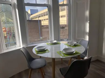 a table and chairs in a room with windows at 3 Smithhills Paisley central spacious sleeps 4 in Paisley
