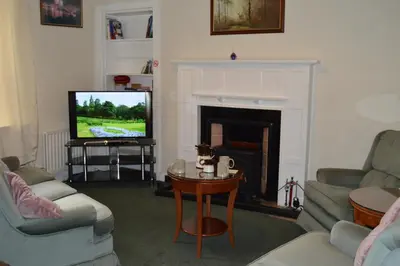 a living room with a tv and a fireplace at Carnegie Holiday Cottage in Dunfermline