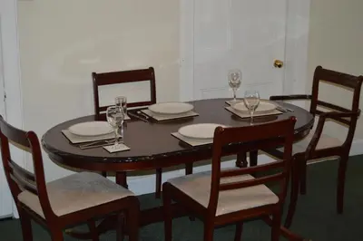 a wooden table with chairs and plates and wine glasses at Carnegie Holiday Cottage in Dunfermline