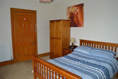 a bedroom with a bed with a wooden bed frame at Carnegie Holiday Cottage in Dunfermline