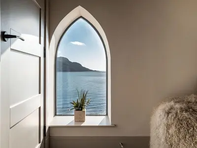 an arched window in a bathroom with a view of the water at Arran Shores Luxury Shorefront Penthouse Suite 12 in Lamlash