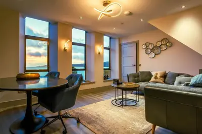 a living room with a couch and a table at Arran Shores Luxury Shorefront Penthouse Suite 12 in Lamlash