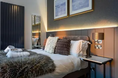 a bedroom with a bed and a table with a lamp at Arran Shores Luxury Shorefront Penthouse Suite 12 in Lamlash