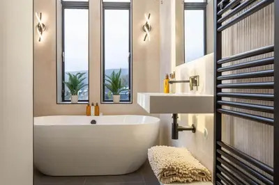 a bathroom with a white tub and a sink and two windows at Arran Shores Luxury Shorefront Penthouse Suite 12 in Lamlash