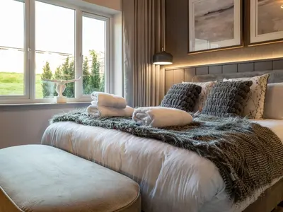 a bedroom with a bed with a blanket and windows at Arran Shores Luxury Shorefront Garden Terrace Apartment 6 in Lamlash