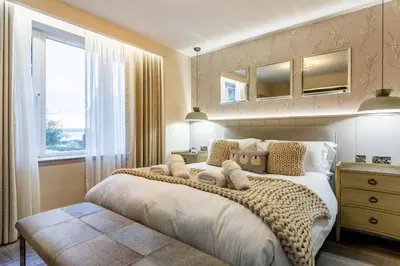 a bedroom with a large bed and a window at Arran Shores Luxury Shorefront Garden Terrace Apartment 6 in Lamlash