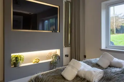 a bedroom with a mirror and a bed with pillows at Arran Shores Luxury Shorefront Garden Terrace Apartment 6 in Lamlash
