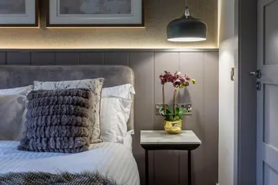 a bedroom with a bed and a vase of flowers on a table at Arran Shores Luxury Shorefront Garden Terrace Apartment 6 in Lamlash