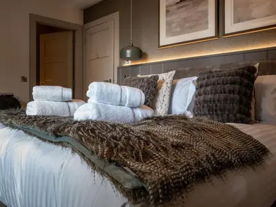 a bed with a blanket and pillows on it at Arran Shores Luxury Shorefront Garden Terrace Apartment 7 in Lamlash