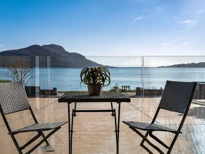two chairs and a table with a potted plant on it at Arran Shores Luxury Shorefront Suite 1 in Lamlash