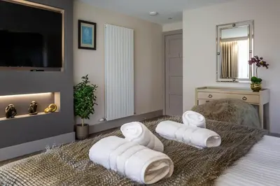 a bedroom with towels on a bed with a television at Arran Shores Luxury Shorefront Apartment 8 in Lamlash