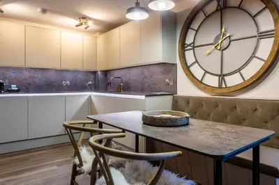 a kitchen with a table and a large clock on the wall at Arran Shores Luxury Shorefront Apartment 8 in Lamlash