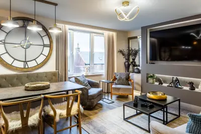 a living room with a large clock on the wall at Arran Shores Luxury Shorefront Apartment 8 in Lamlash