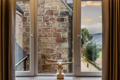 a window with a view of a brick wall at Arran Shores Luxury Shorefront Apartment 8 in Lamlash