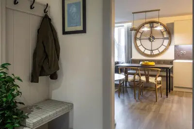 a dining room with a table and a clock on the wall at Arran Shores Luxury Shorefront Apartment 9 in Lamlash