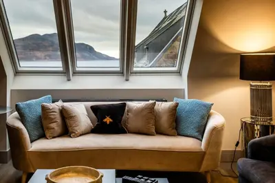 a couch with pillows in a room with windows at Arran Shores Luxury Shorefront Penthouse Suite 11 in Lamlash