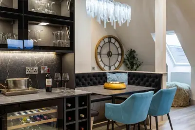 a dining room with a table and chairs and a clock at Arran Shores Luxury Shorefront Penthouse Suite 11 in Lamlash