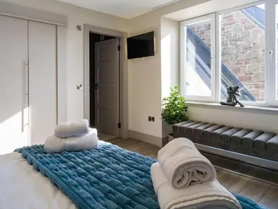 a bedroom with a bed with a blue blanket and a window at Arran Shores Luxury Shorefront Penthouse Suite 10 in Lamlash