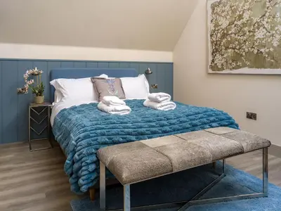 a bedroom with a blue bed with towels on it at Arran Shores Luxury Shorefront Penthouse Suite 13 in Lamlash