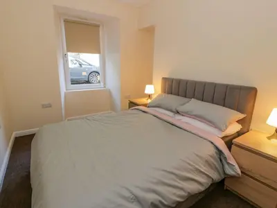 a bedroom with a bed with two lamps and a window at 8 George Street in Millport