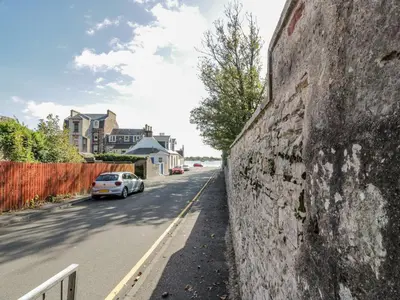 a stone wall with a car parked on the side of a street at 8 George Street in Millport
