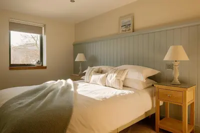 a bedroom with a large white bed and a window at Brenachoile Cottage in Callander