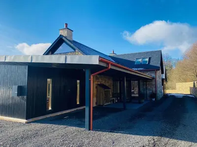 a house with a garage with a roof at Brenachoile Cottage in Callander