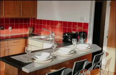 a kitchen with a table with plates and wine glasses at Glasgow City Centre Apartment in Glasgow