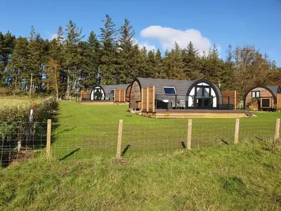 a house in a field with a fence at East Rigg Lodges in Balerno