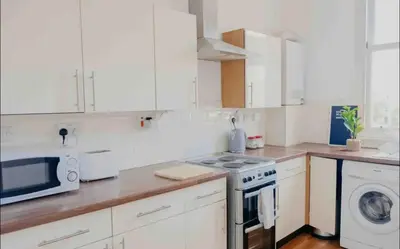 a white kitchen with a stove and a microwave at Glasgow City 1 Bedroom Apartment in Glasgow