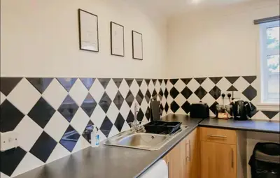 a kitchen with a sink and a checkered wall at Glasgow - 1 Bedroom Apartment in Glasgow