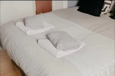 two stacks of towels on a white bed at Glasgow - 1 Bedroom Apartment in Glasgow