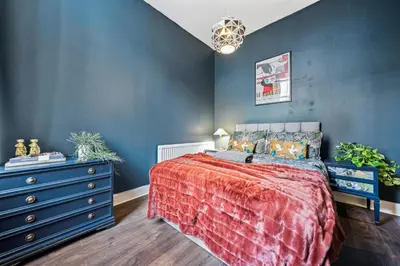a bedroom with a bed and a blue wall at Grand 2 Bed West End Residence in Glasgow