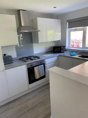 a kitchen with white cabinets and a stove top oven at Garden flat in Largs