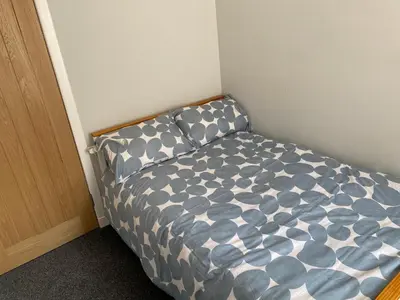 a small bed in a corner of a room at Garden flat in Largs