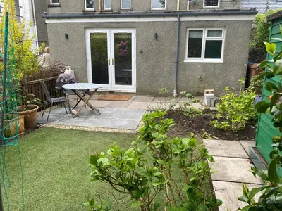 a garden with a patio with a table and a door at Garden flat in Largs