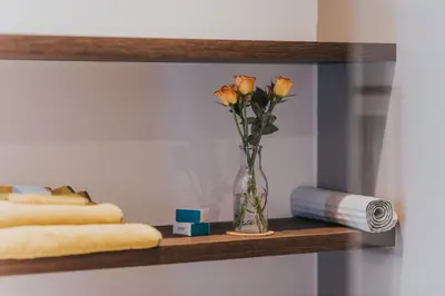 a vase of flowers on a shelf with towels at Scottish Apartment with Amazing Castle Views in Edinburgh