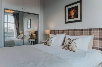 a bedroom with a large bed with white sheets and pillows at Scottish Apartment with Amazing Castle Views in Edinburgh