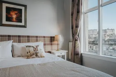 a bed with a pillow on it in a bedroom with a window at Scottish Apartment with Amazing Castle Views in Edinburgh