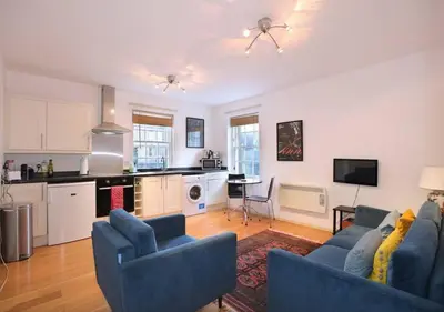 a living room with two blue couches and a kitchen at Grassmarket Apartment with Amazing Castle View in Edinburgh