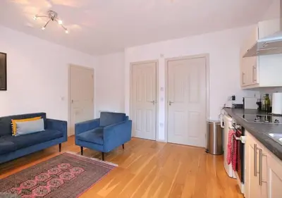 a living room with a blue couch and a kitchen at Grassmarket Apartment with Amazing Castle View in Edinburgh